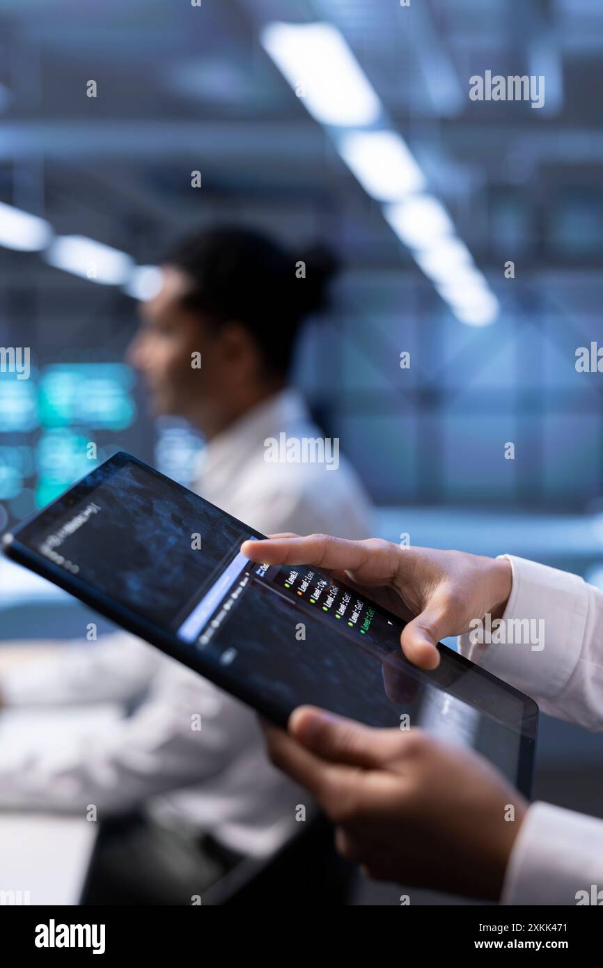 Computer scientist using tablet, optimizing data center performance. Close up of IT professional using device to troubleshoot mainframes, ensuring optimal performance and minimizing downtime Stock Photo