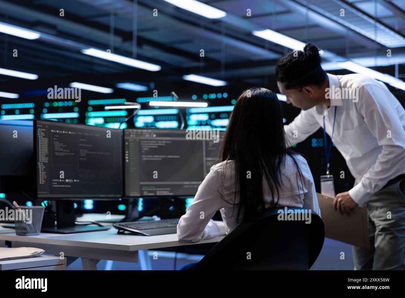 Teamworking technicians in server room looking to find network issues affecting supercomputer performance. IT experts fixing slow data transfer rates in data center equipment Stock Photo