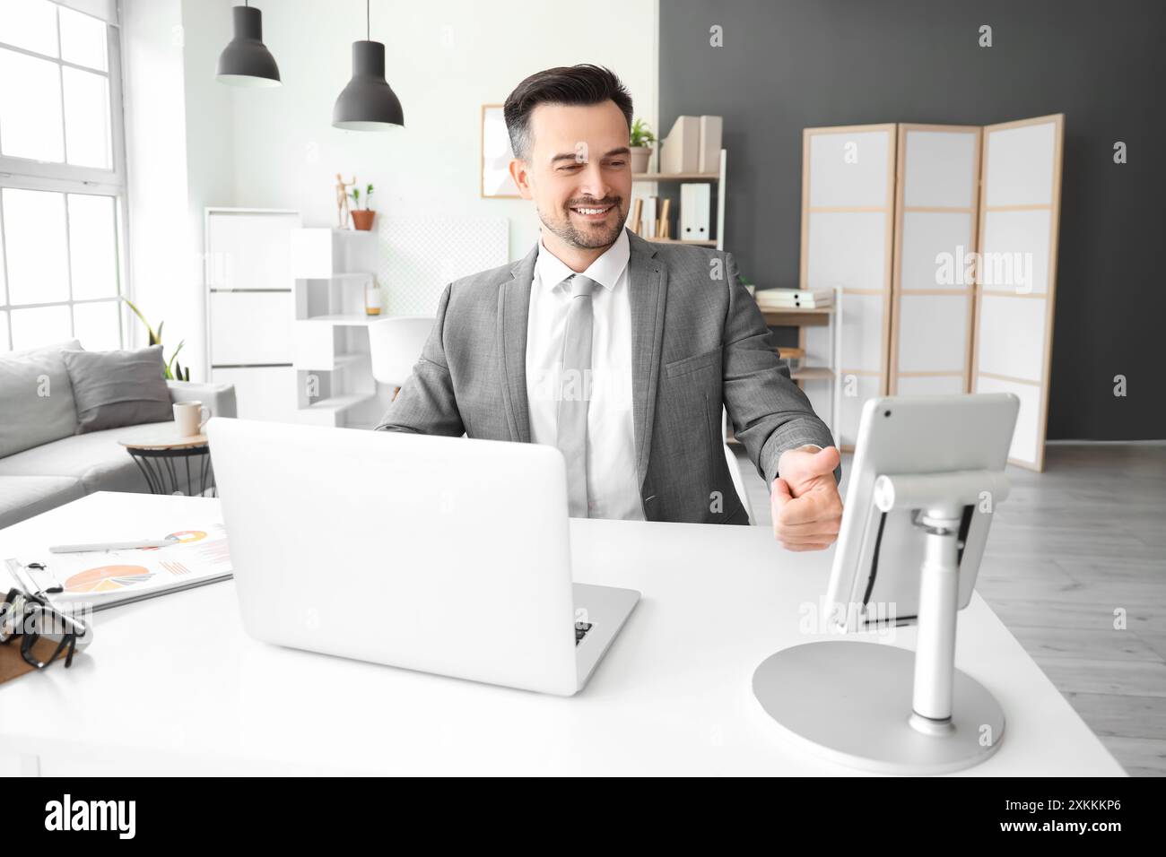 Young businessman unlocking tablet computer at table in office Stock Photo