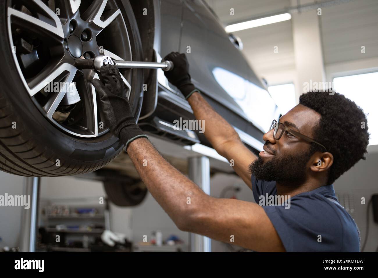 Mechanic working on car wheel in auto repair shop Stock Photo - Alamy