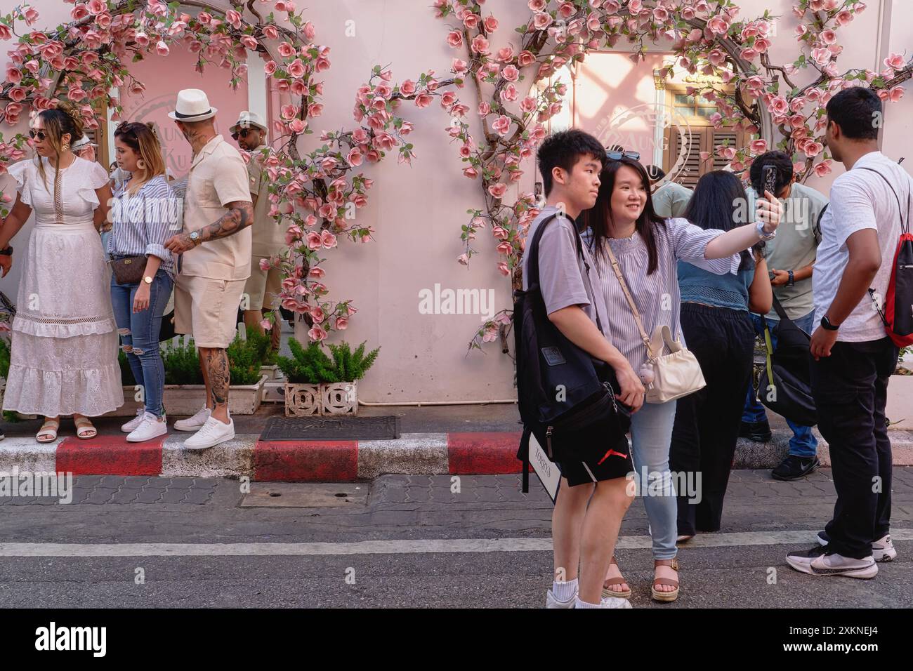 A young Chinese tourist couple at a popular photo spot in Soi Romanee (Rommani) in the Old Town area of Phuket Town, Thailand, taking selfies Stock Photo