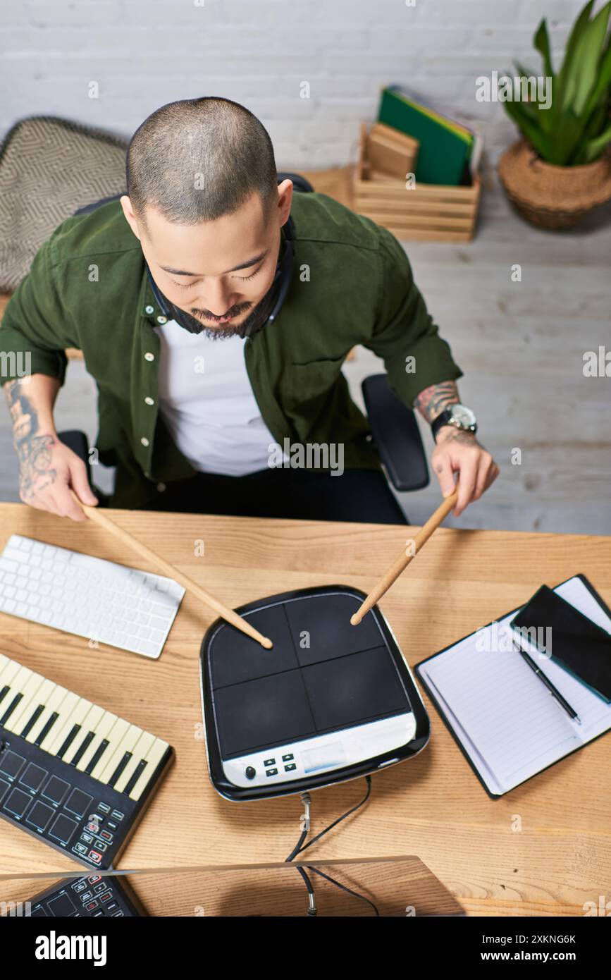 A young Asian man plays drums in a music studio. Stock Photo