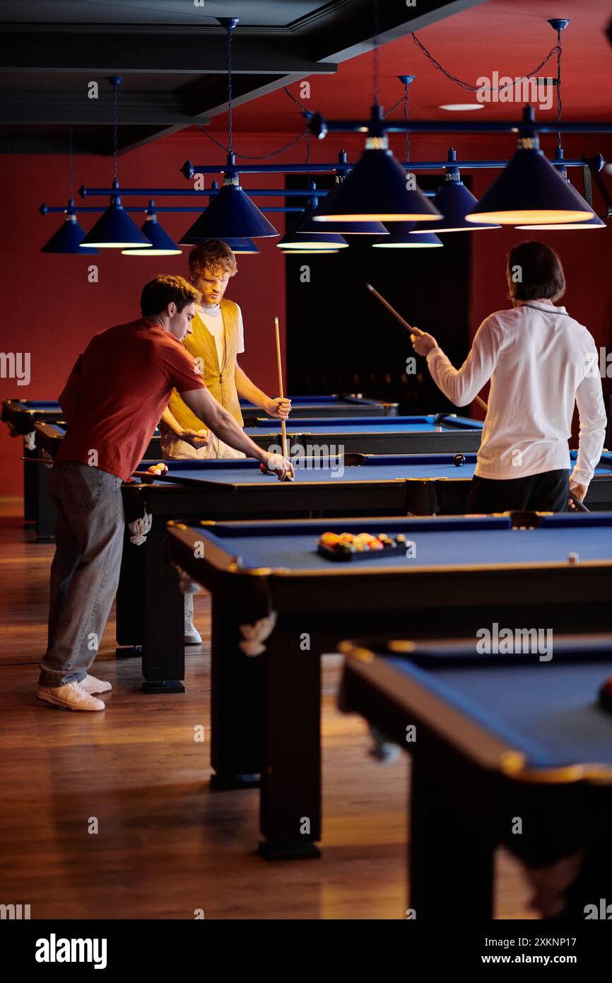 Friends play billiards in a dimly lit room, enjoying a fun evening out. Stock Photo