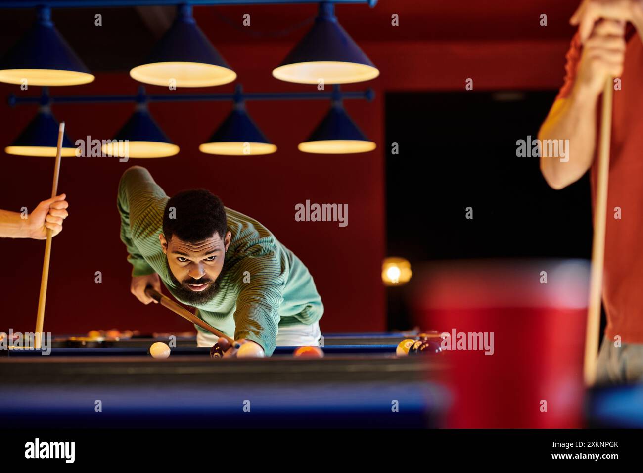 Friends play billiards in a stylishly lit room. Stock Photo