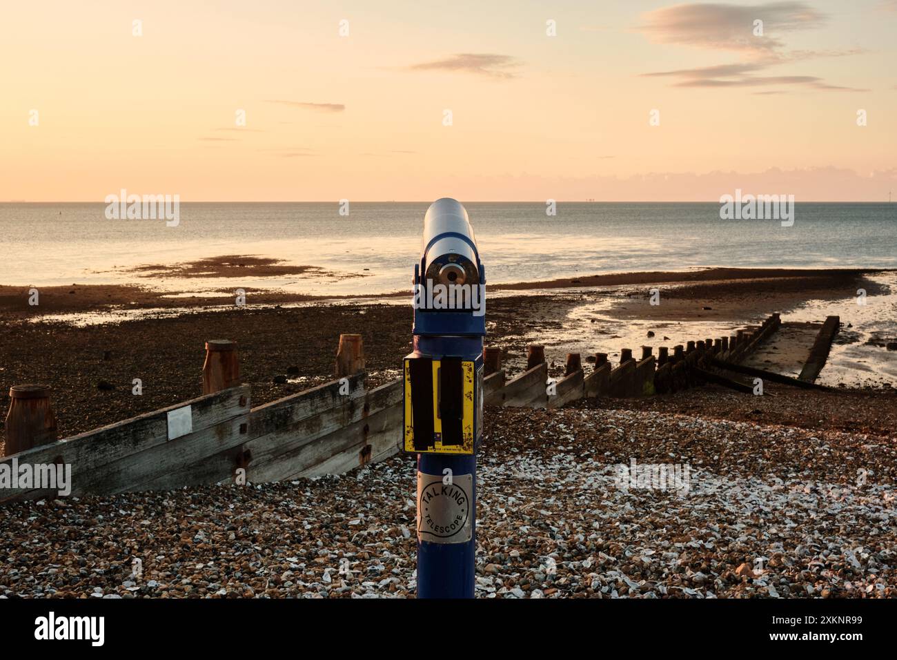 A viewing talking telescope on Whitstable east quay beach looking out to sea over the Thames estuary at sunset. Stock Photo