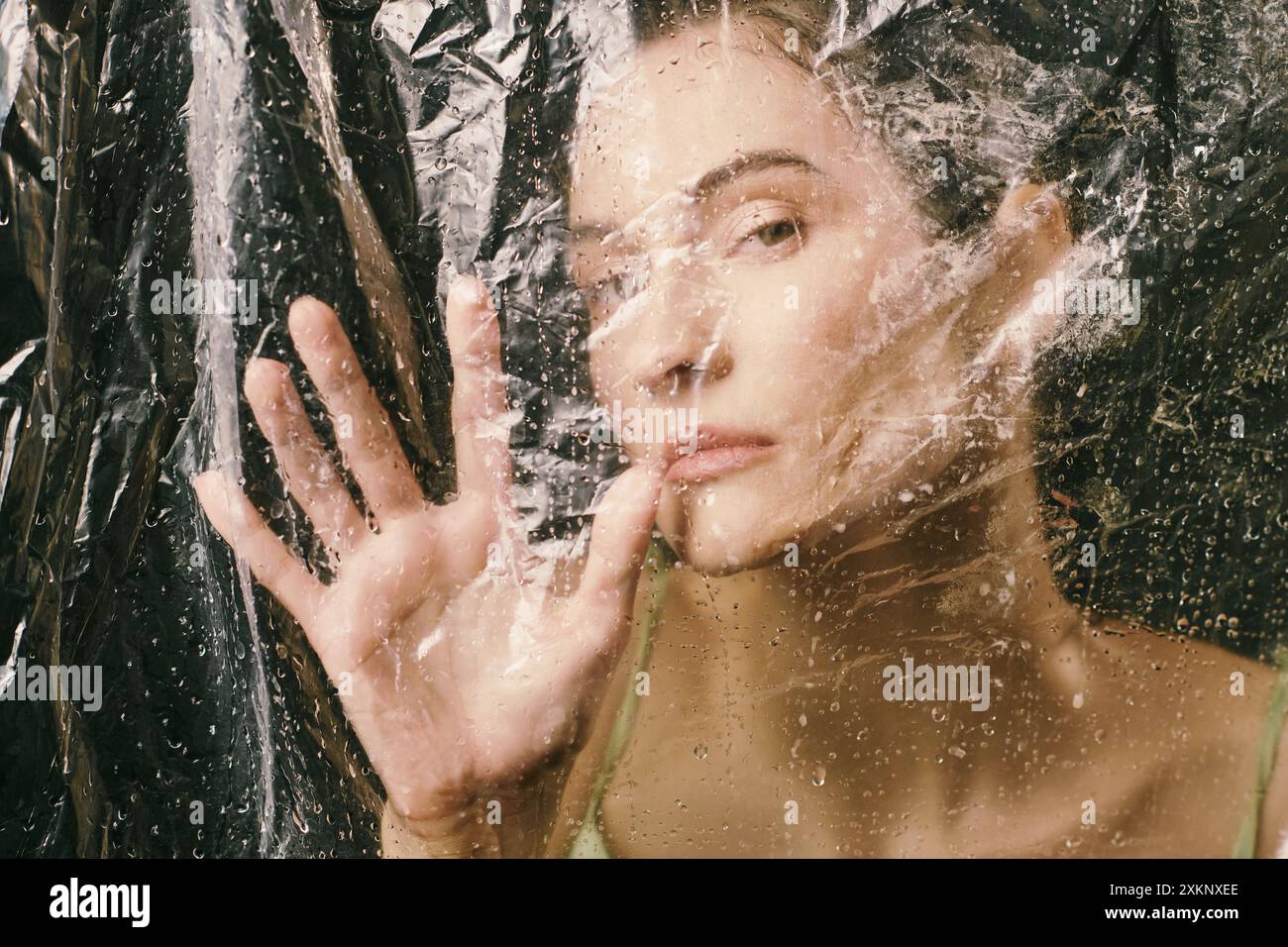 A womans face is partially obscured by a sheet of plastic, rain ...