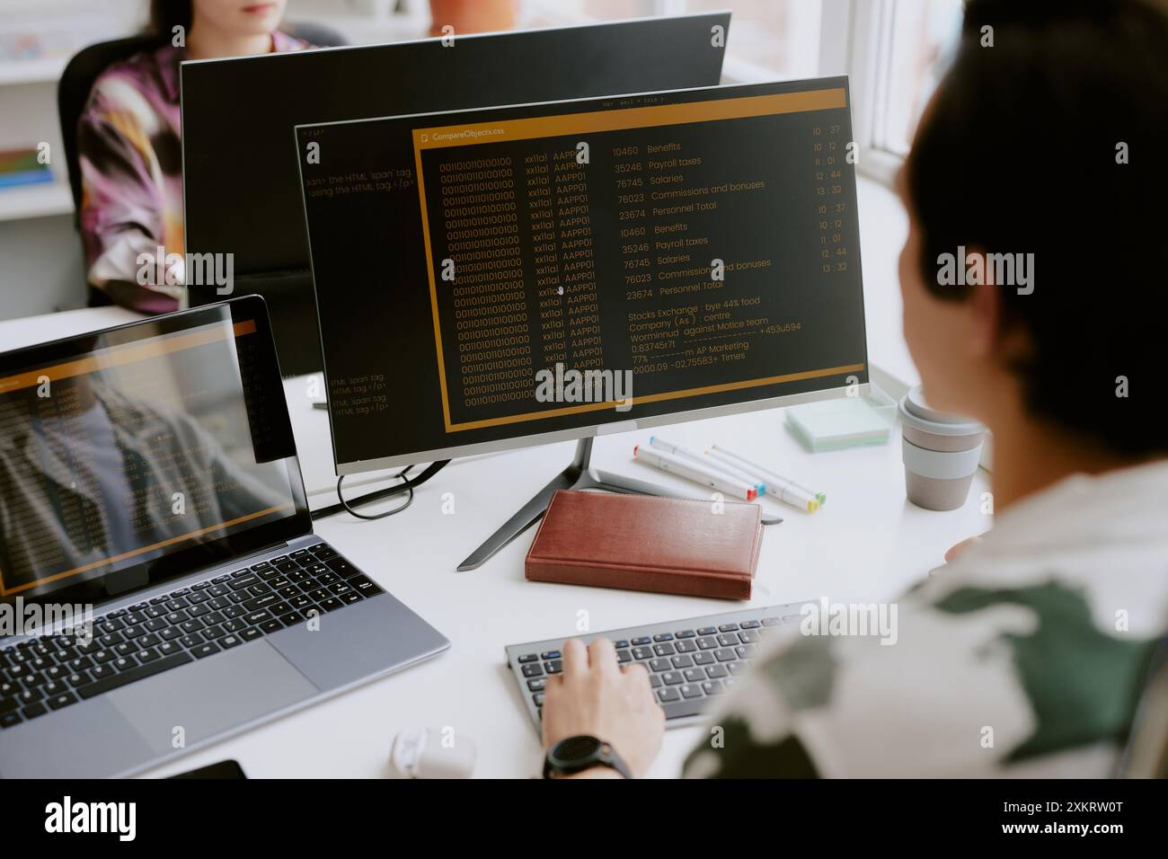 Over shoulder shot of male programmer surrounded by computers looking ...