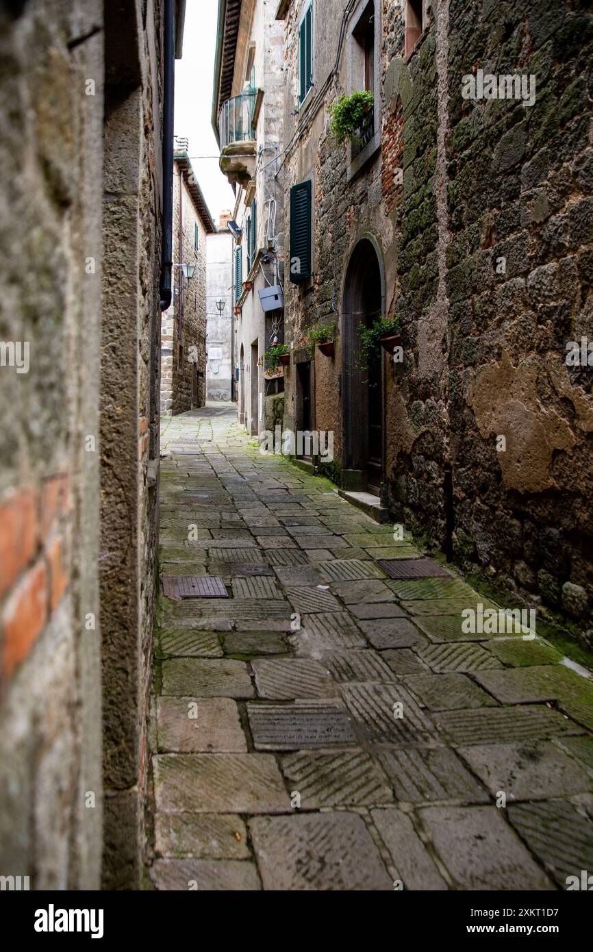 A narrow, dimly lit, tiled street, among the stone houses, Monte Amiata area, Siena, Tuscany, Italy Stock Photo