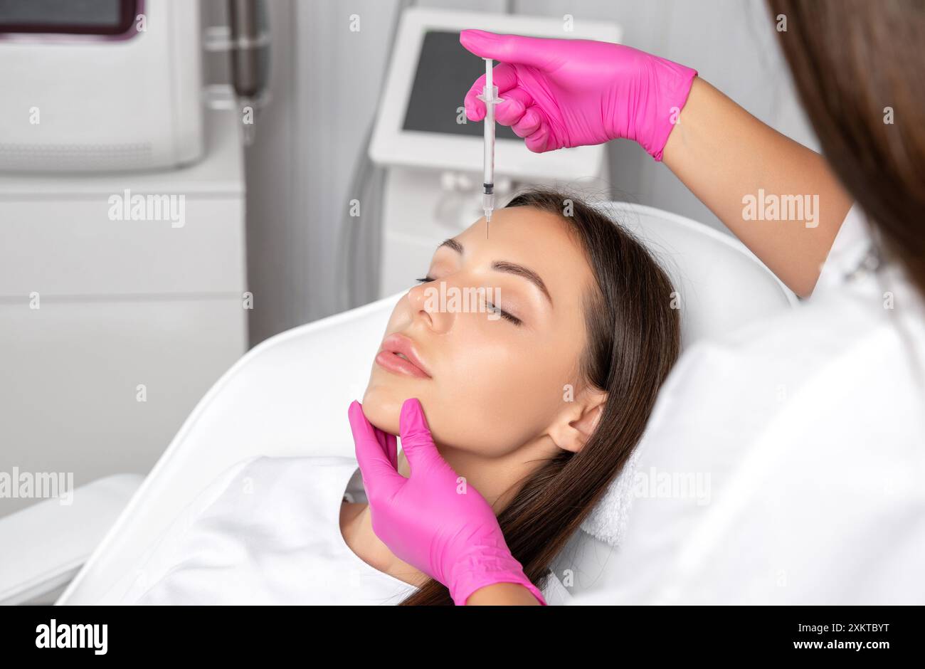 Woman at the beautician. Cosmetologist does anti wrinkle injections on the forehead and between eyebrows. Women's cosmetology in the beauty salon. Stock Photo