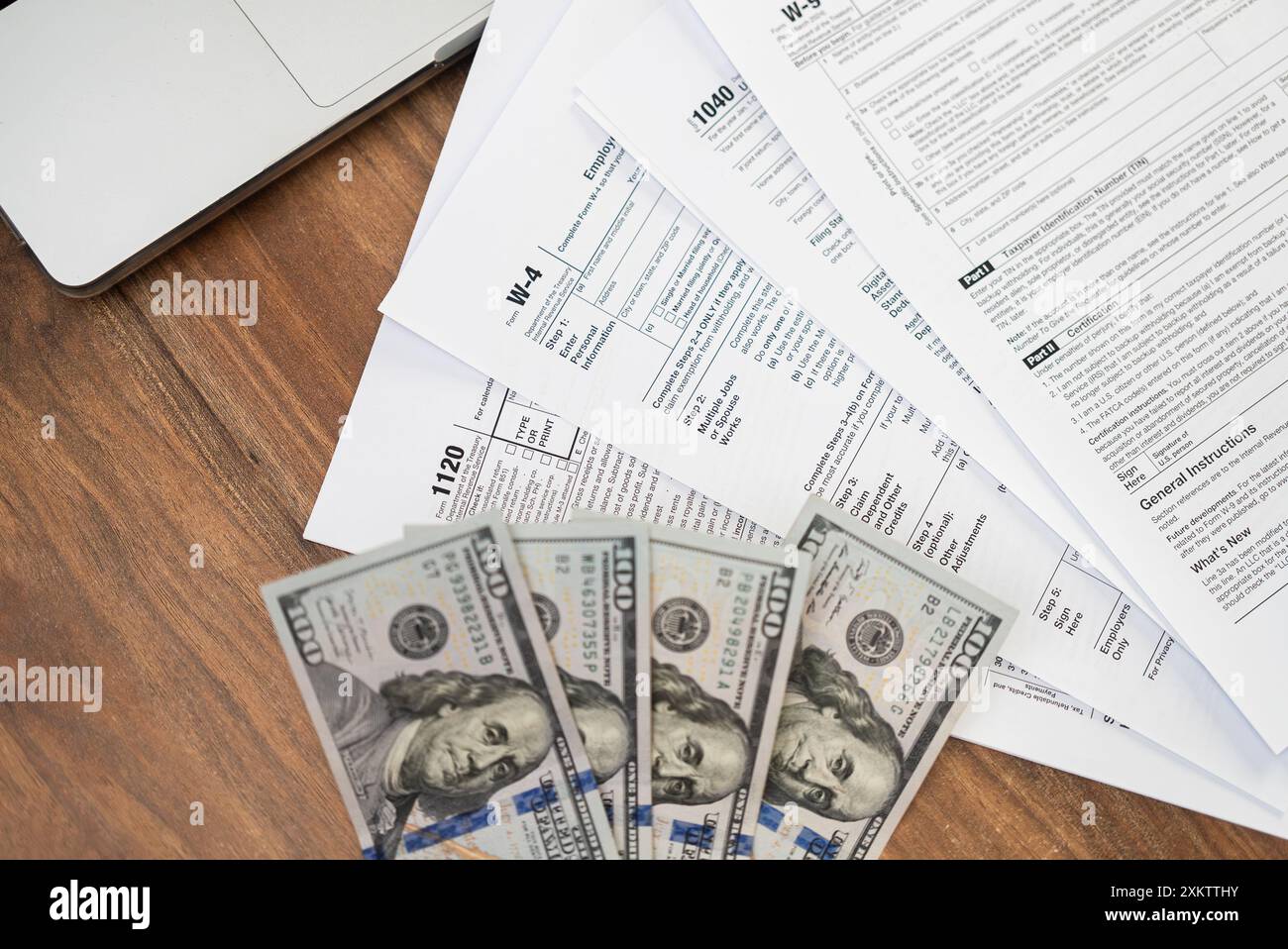Assortment of tax forms near open laptop and dollar bills creating ...