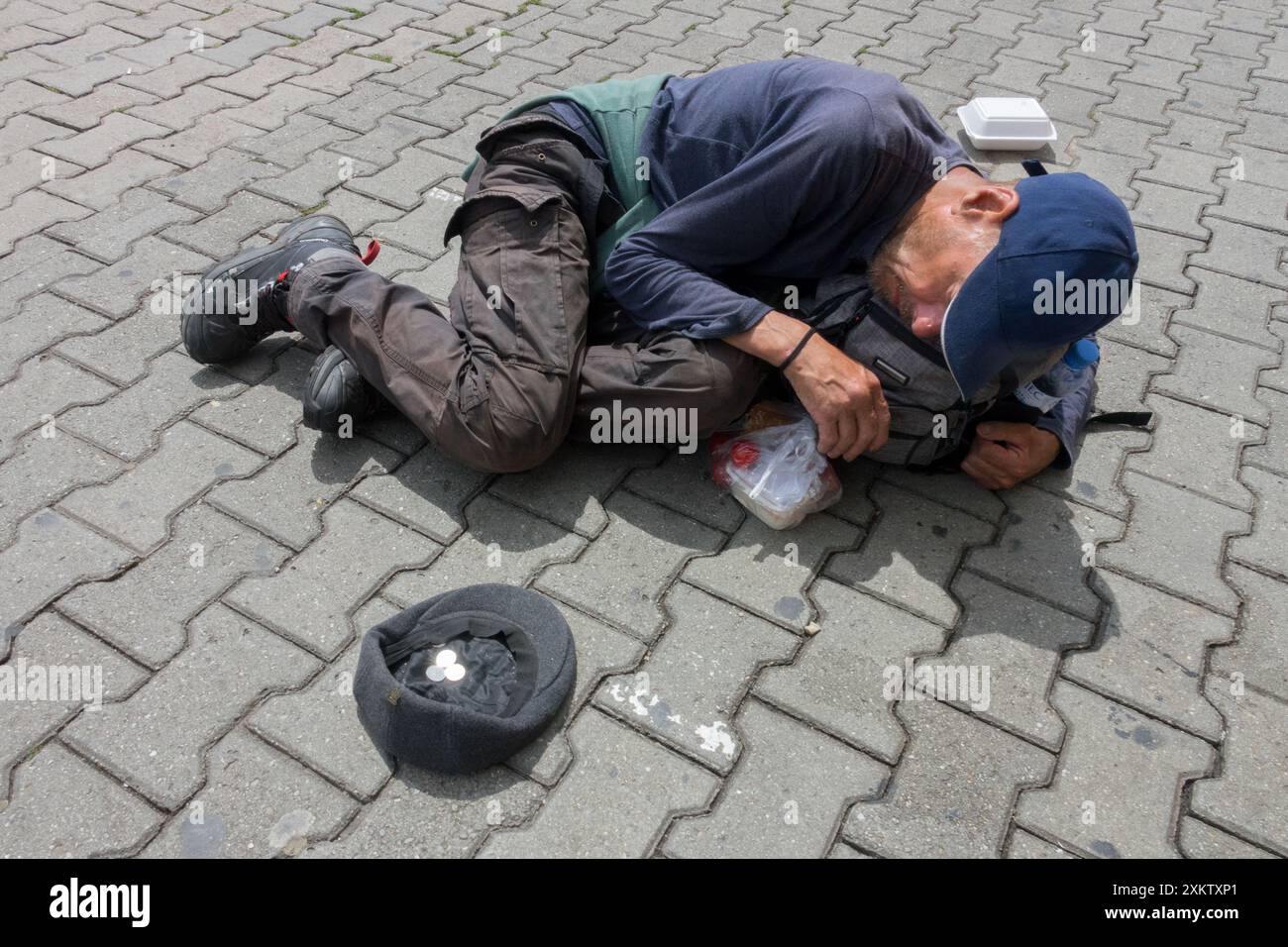 a drugged man lying on the street for money, a poor vagabond Homeless Crouched Position Stock Photo