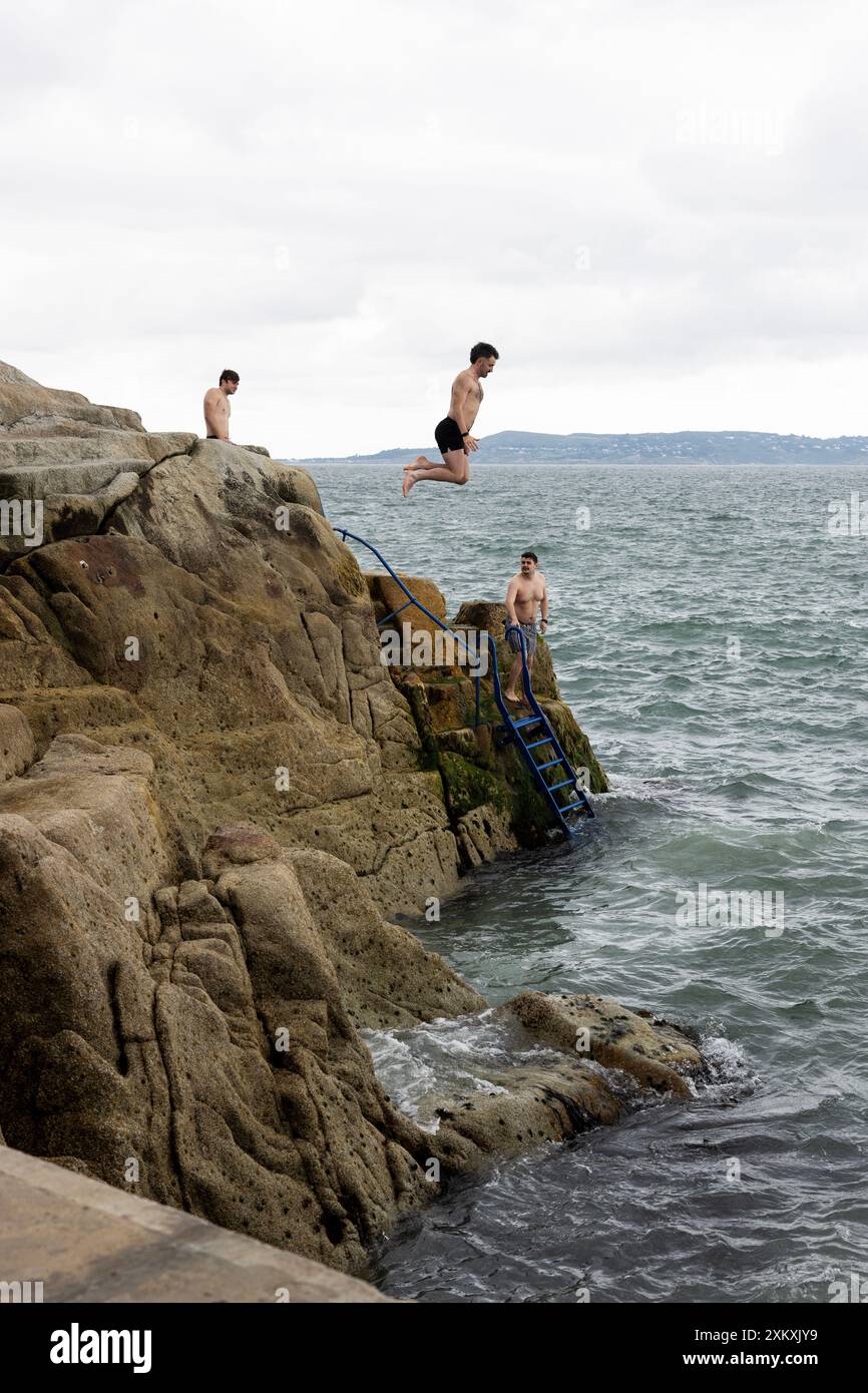 Swimmers jump off the rocks at Forty Foot, a famous swimming spot in ...