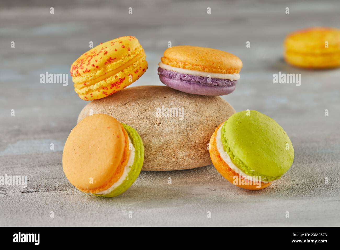 Colorful macarons with stone on concrete background. Stock Photo