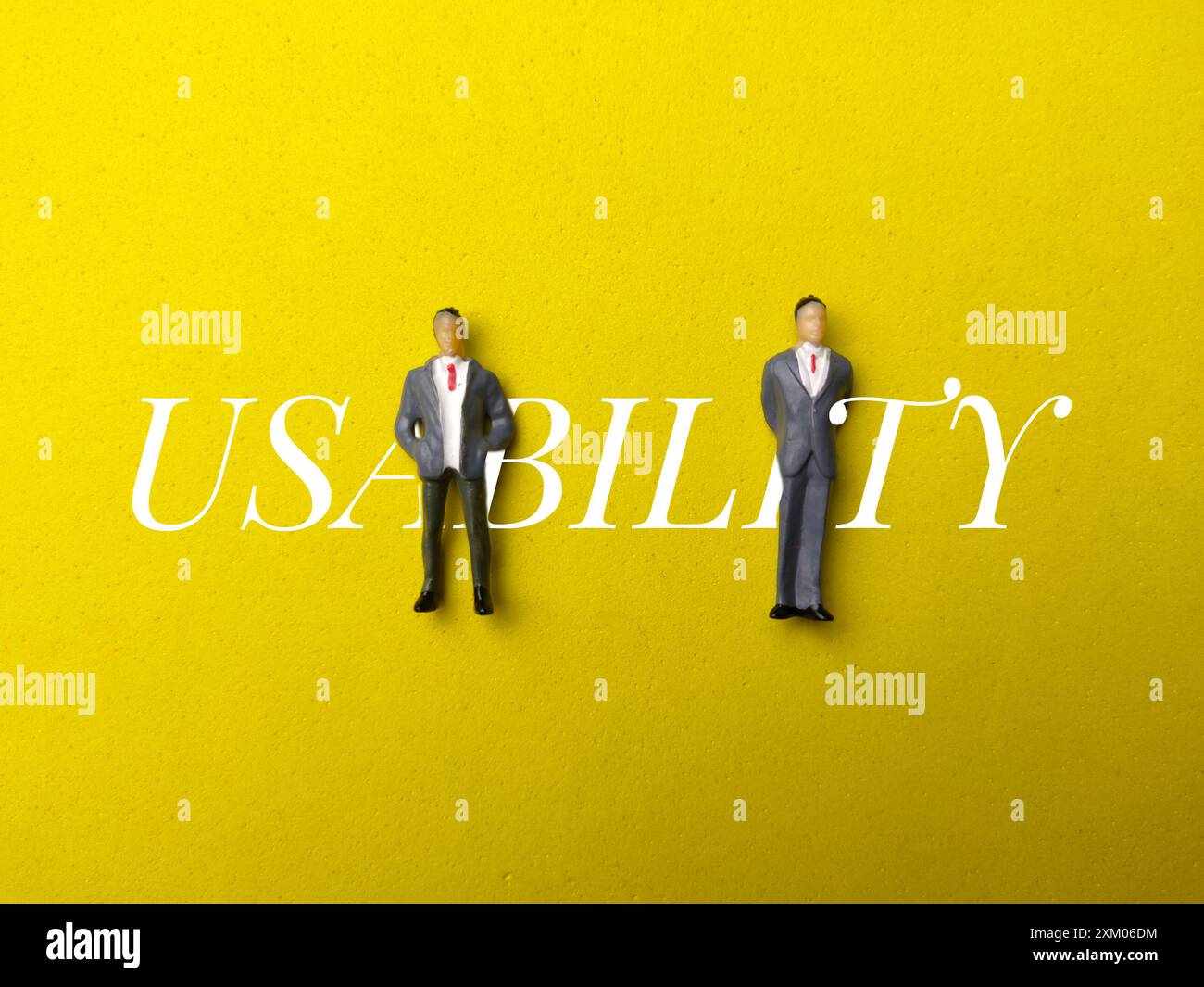 Miniature people with word USABILITY on yellow background. Stock Photo