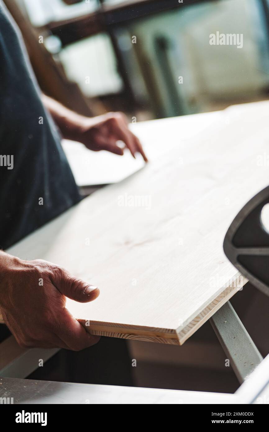 Skilled carpenter examining plywood in workshop, showcasing craftsmanship. Close up highlights wood grain texture, tools, sawdust convey labor and ind Stock Photo