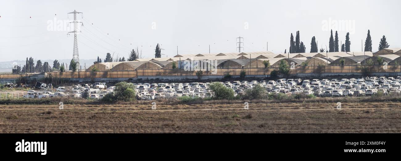 a small section of the rows and rows of cars attacked and ruined by the Hamas invasion of Israel on 7 October with a clear sky and farmland Stock Photo