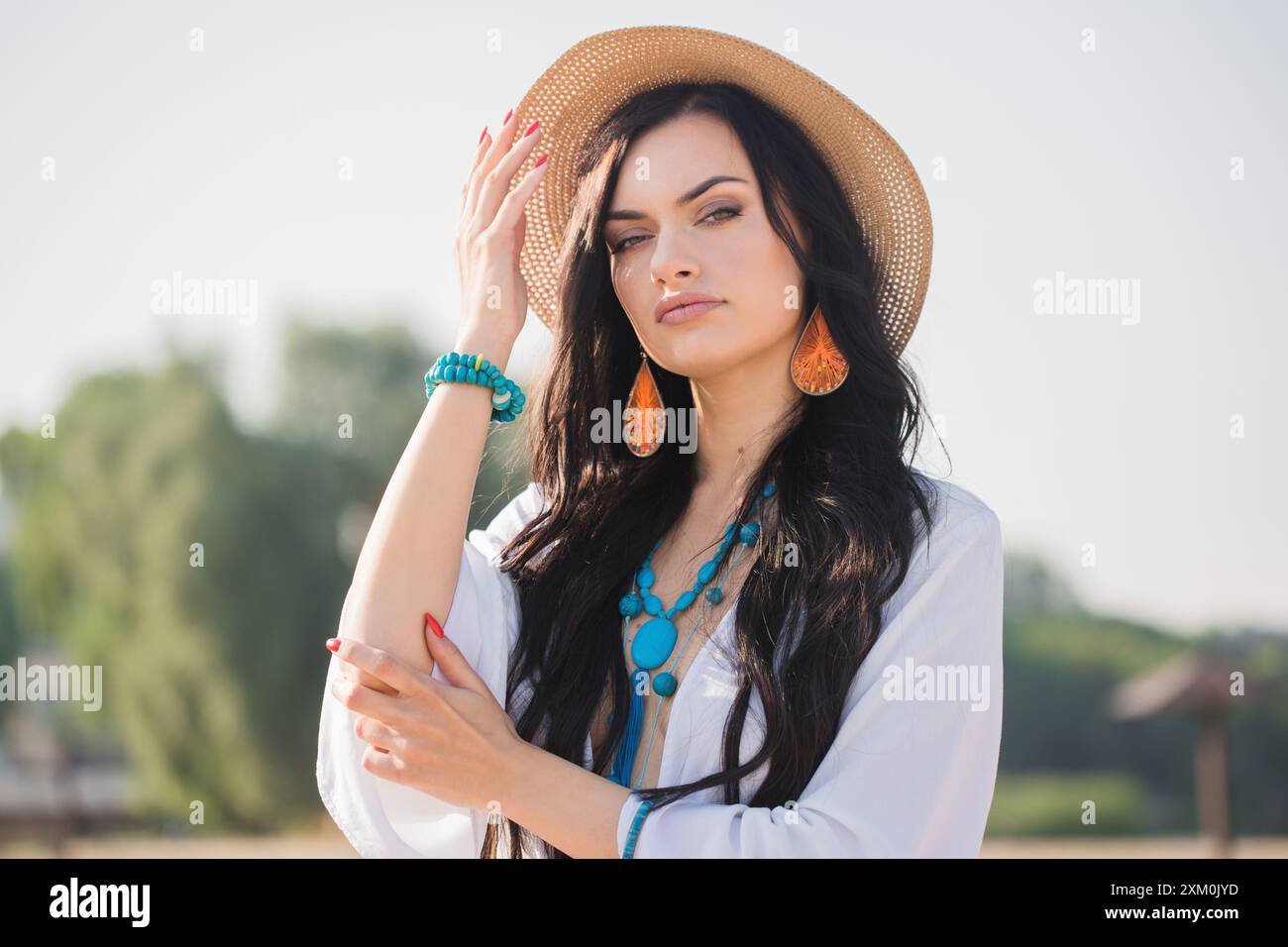 Portrait of a young woman with long dark hair in a hat on the beach in ...
