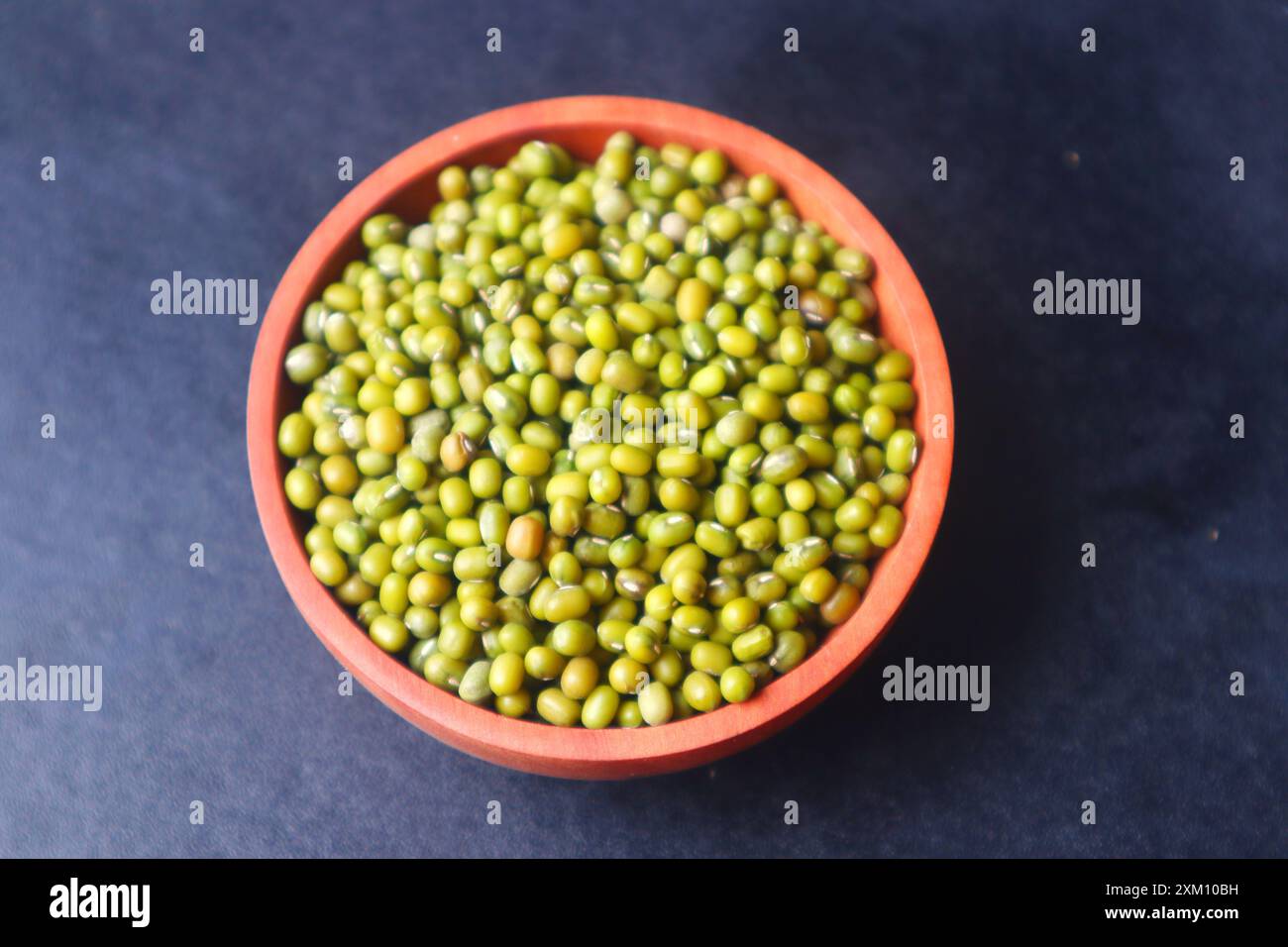 Green beans (Vigna radiata) in a wooden bowl close up on black background. Stock Photo