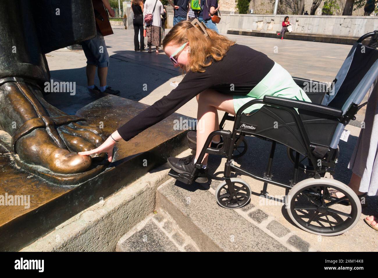 Touching big toe on foot for luck girl in wheelchair disabled child