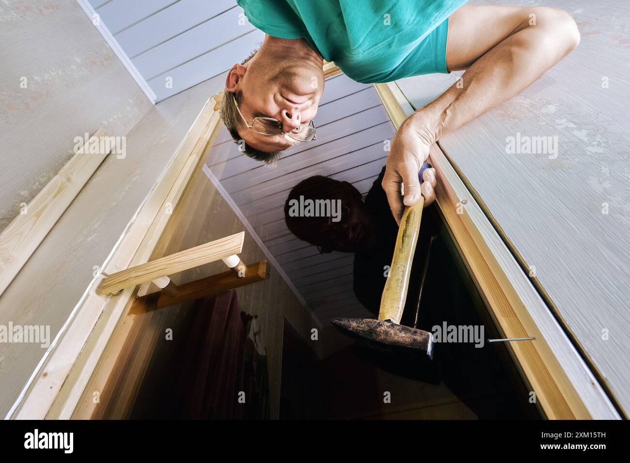 Carpenter using hammer to secure jamb to door frame, beginning with hinge side. Stock Photo