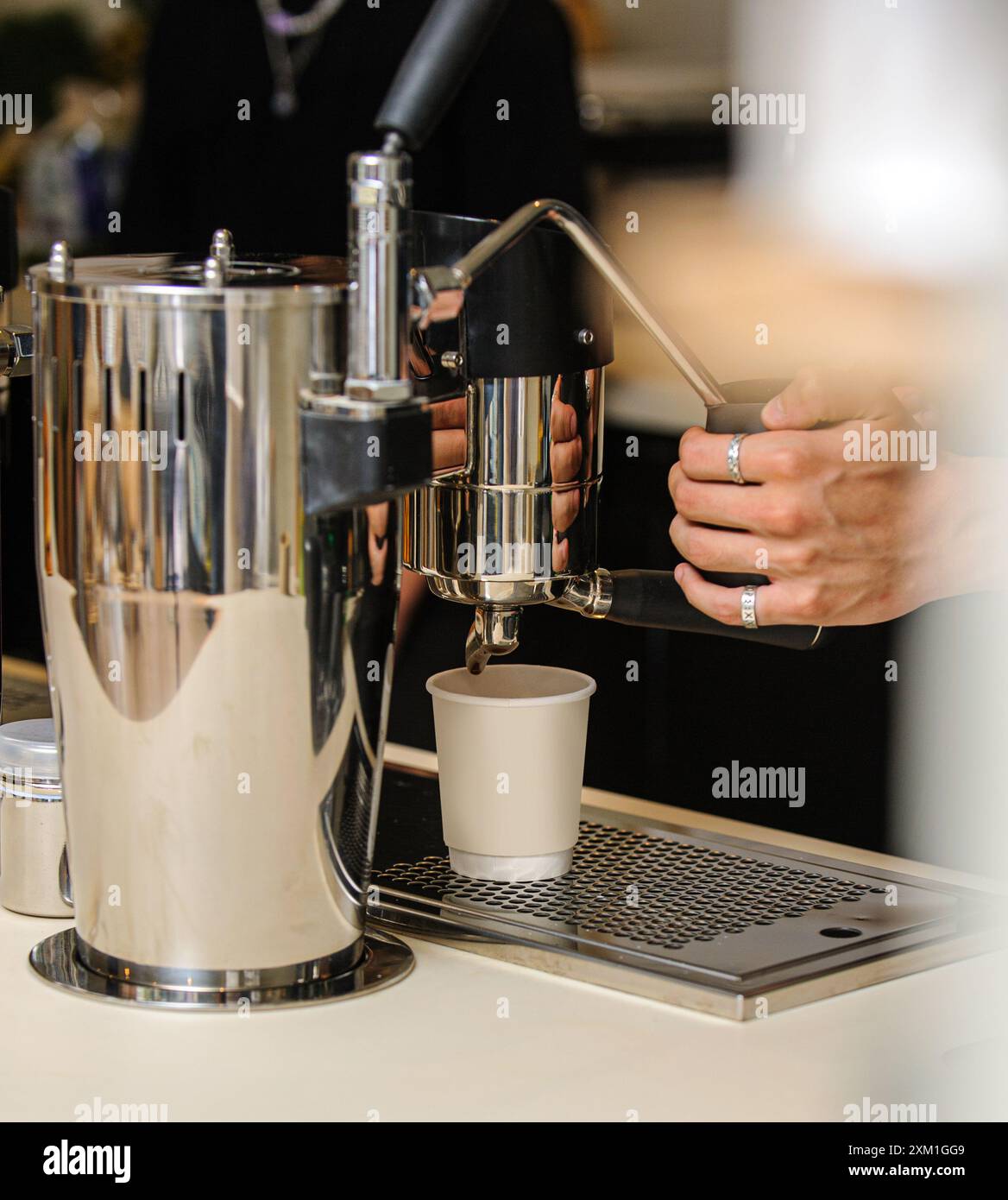 Male hands pouring milk and preparing fresh cappuccino. Coffee artist. Stock Photo