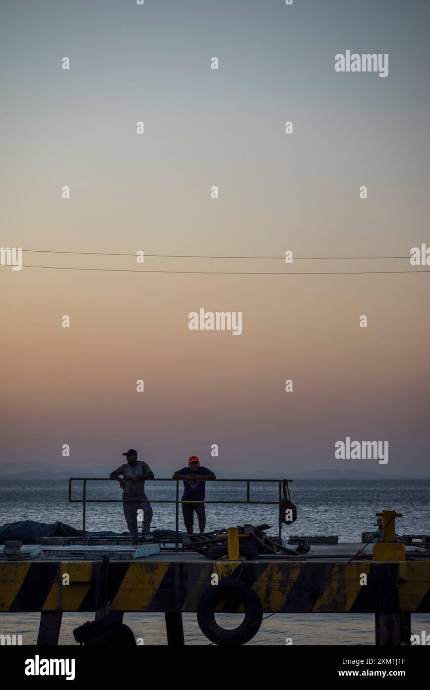 Two workmen at the harbour at twilight, Ometepe island, Lake Nicaragua,  Rivas Department, Nicaragua Stock Photo