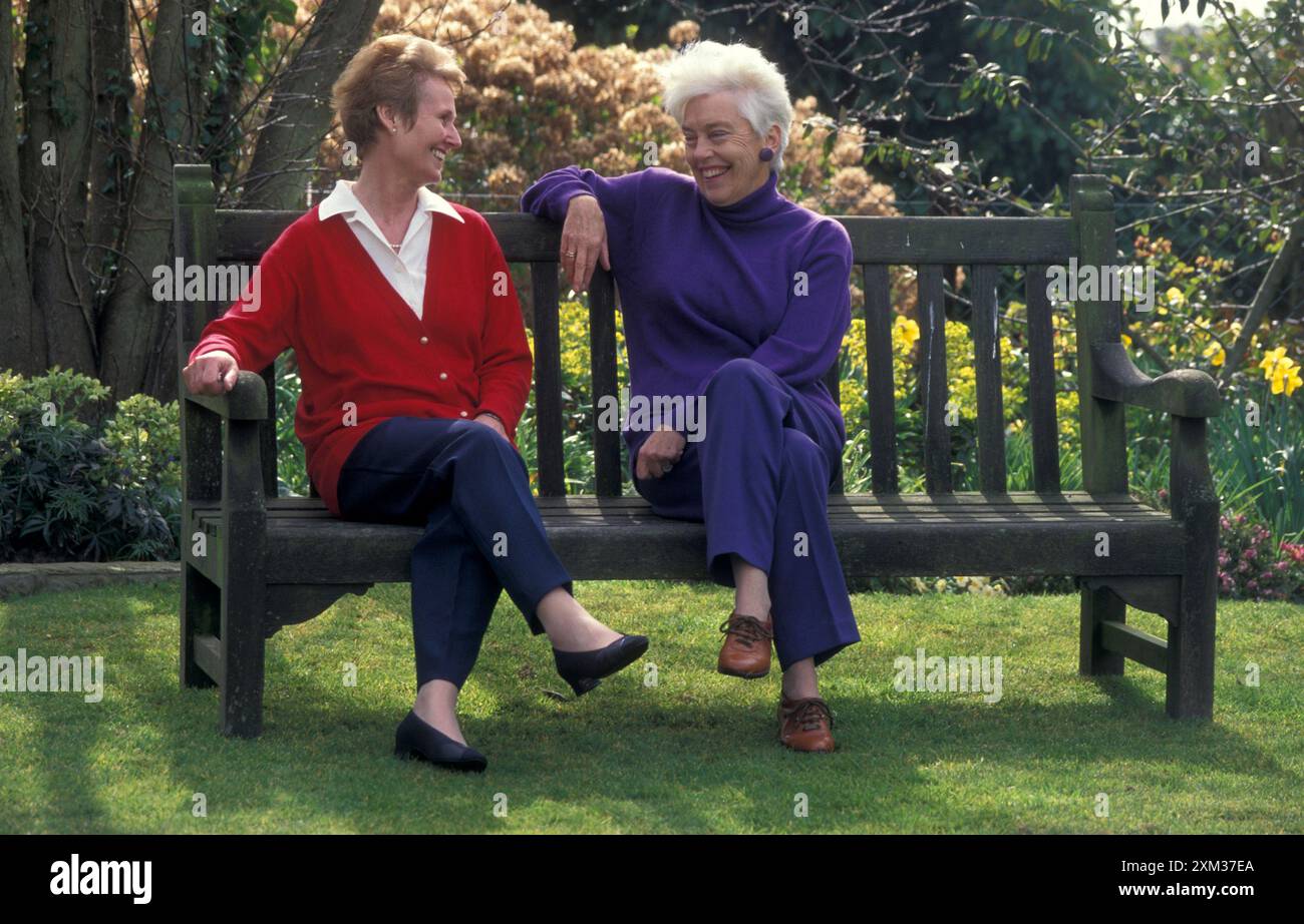 two mature women chatting on bench Stock Photo