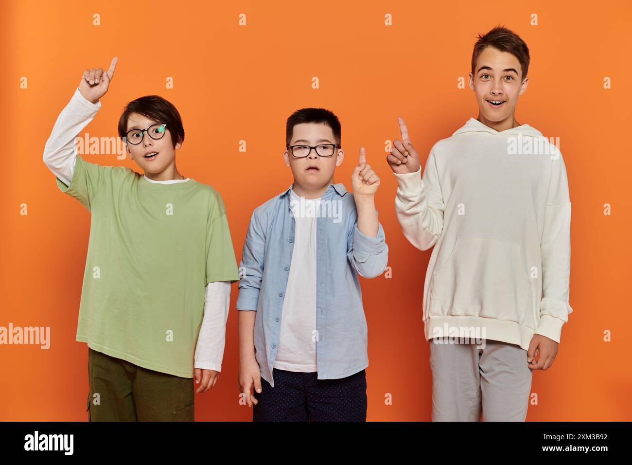 Three boys stand together, pointing upwards in a gesture of unity and ...
