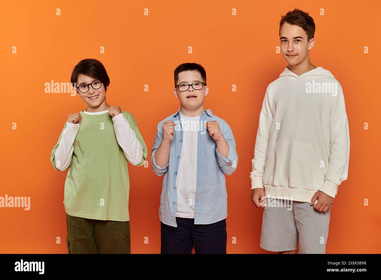 Three boys stand in front of a bright orange background Stock Photo - Alamy