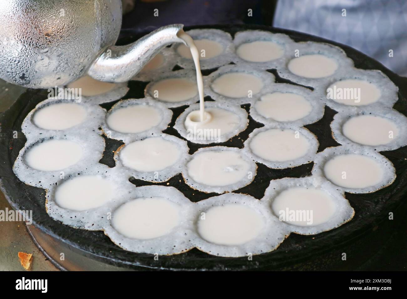 Kanom krok or Thai Coconut Milk Pancakes Batter Being Poured in the Pan's Holes Stock Photo