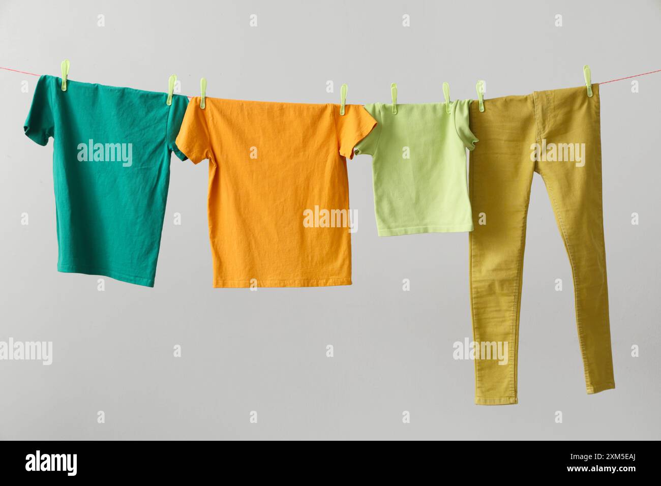 Clean clothes hanging on rope against grey background Stock Photo - Alamy