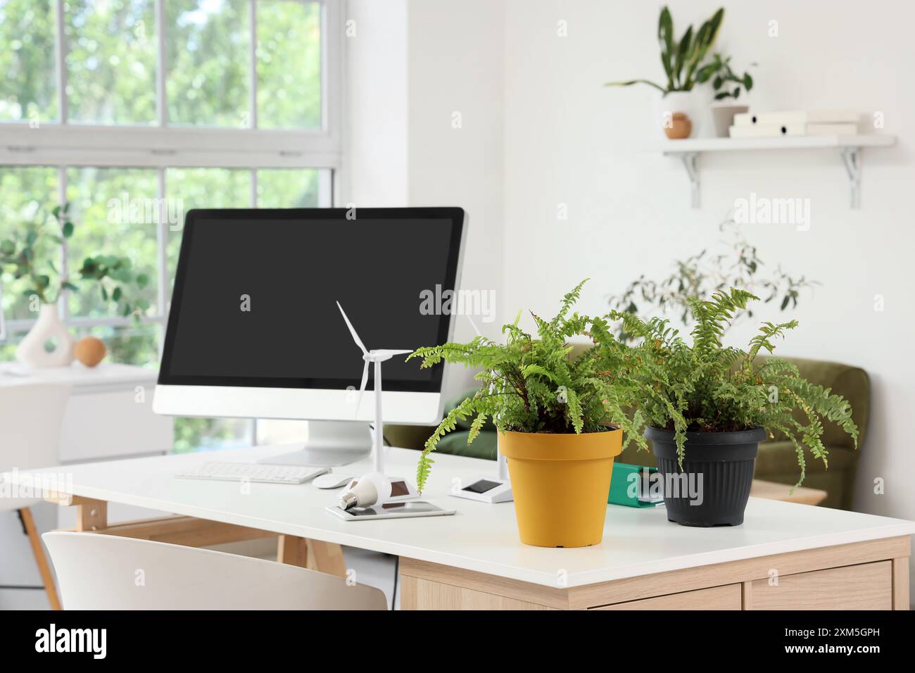 Engineer's workplace with computer monitor, plants and wind turbine ...
