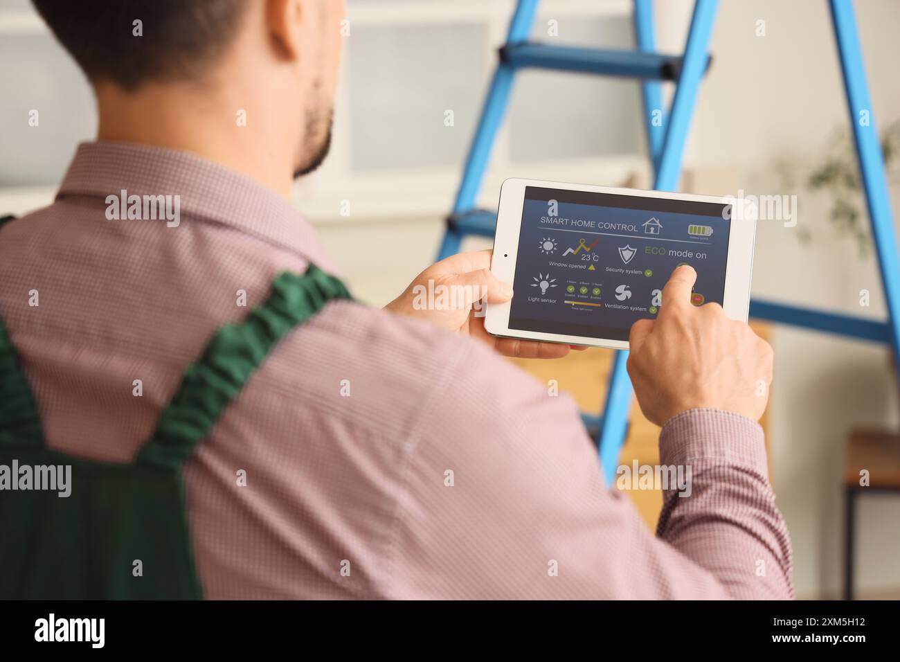 Male worker using tablet computer with installed alarm system in room ...