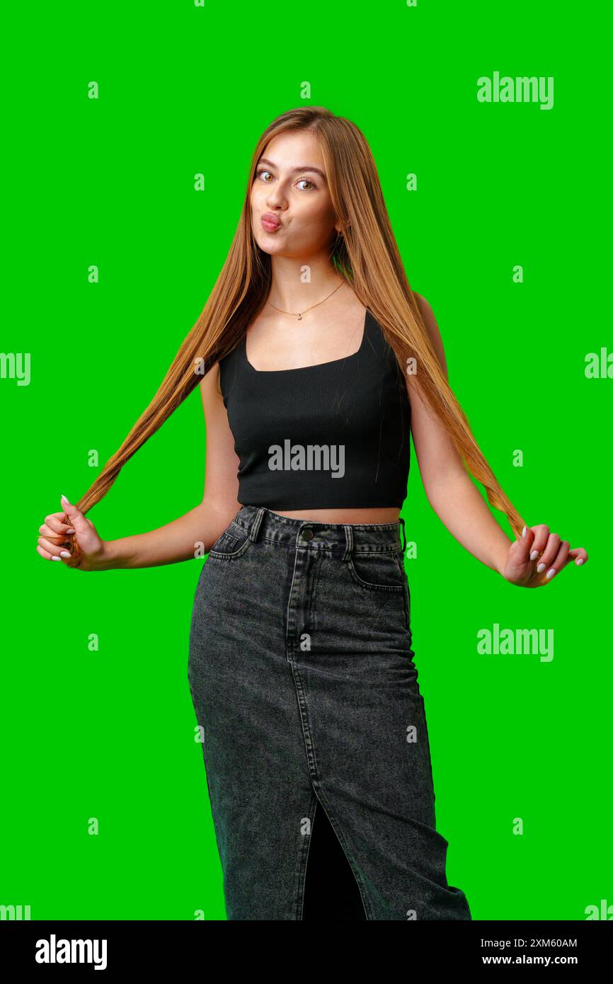 Young Woman With Long Brown Hair Holding Her Hair in Front of a Green ...
