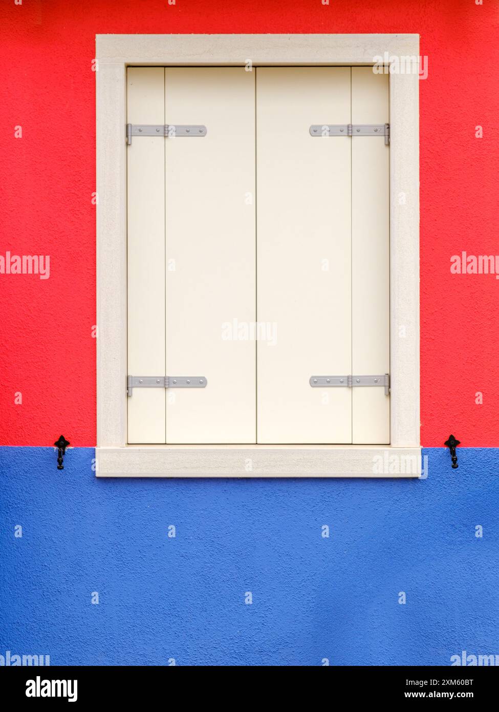 A vibrant red and blue window creates a striking contrast, showcasing Burano's love for bold and playful color combinations.' Stock Photo