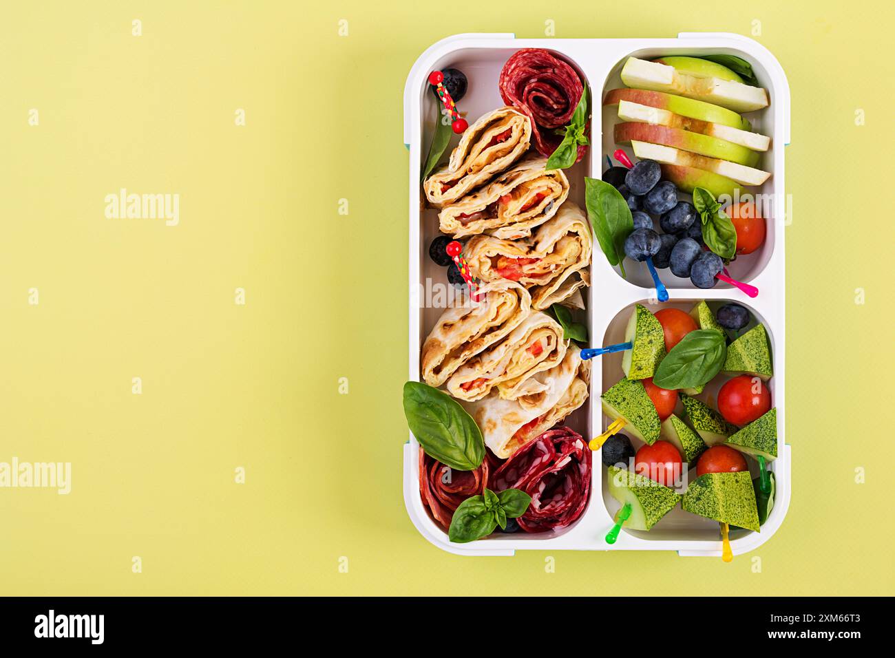 Kids lunch box with tortilla roll, sausage, cherry tomatoes and ...