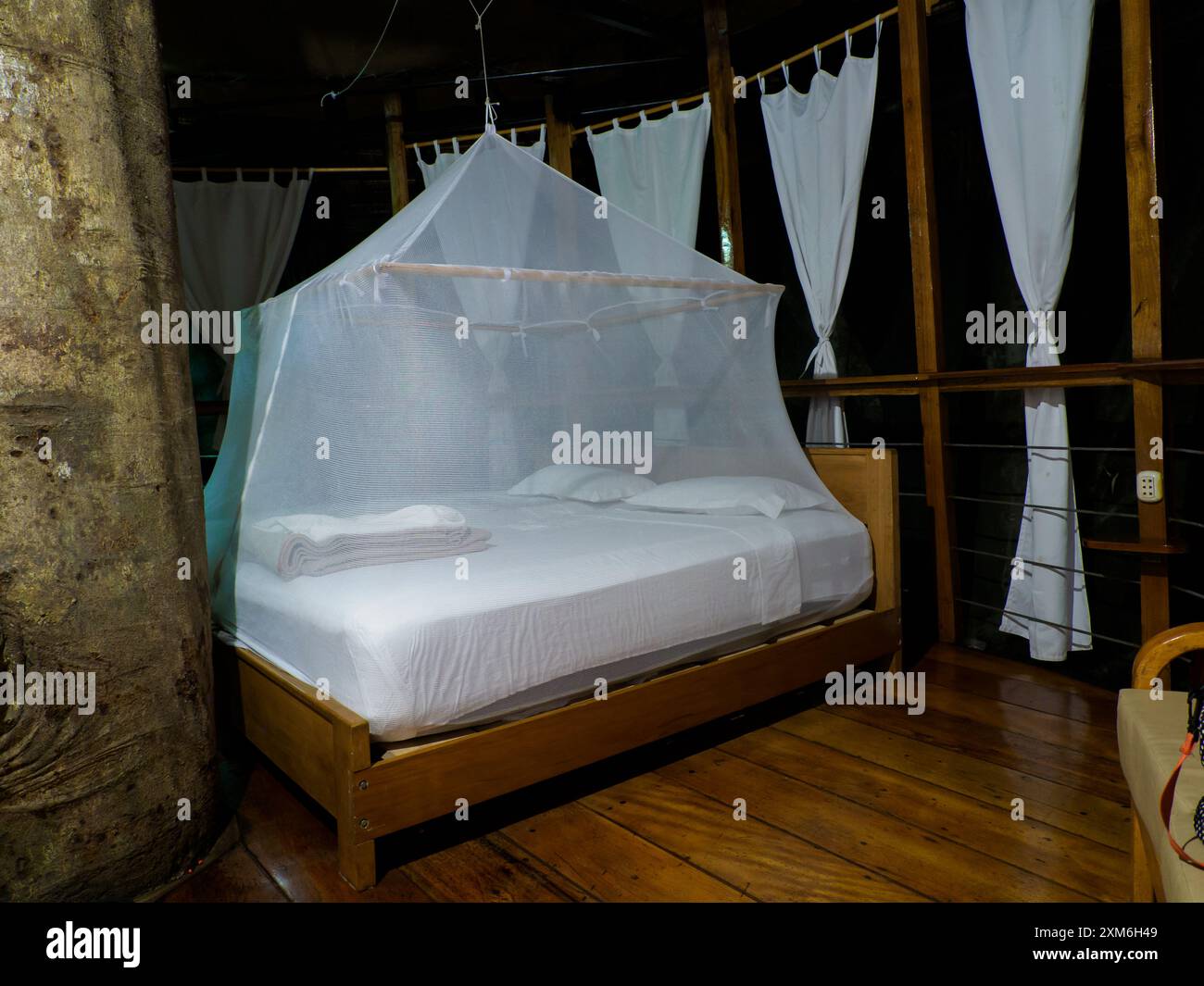 Nauta, Peru - Apr, 2022: Huge bed with white mosquito net. Glamping accommodation in the Amazon rainforest. Wooden treehouse , Amazon Rainforest, Amaz Stock Photo