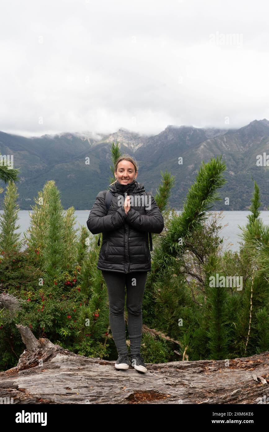 A woman is standing on a rock in the woods, wearing a black jacket ...