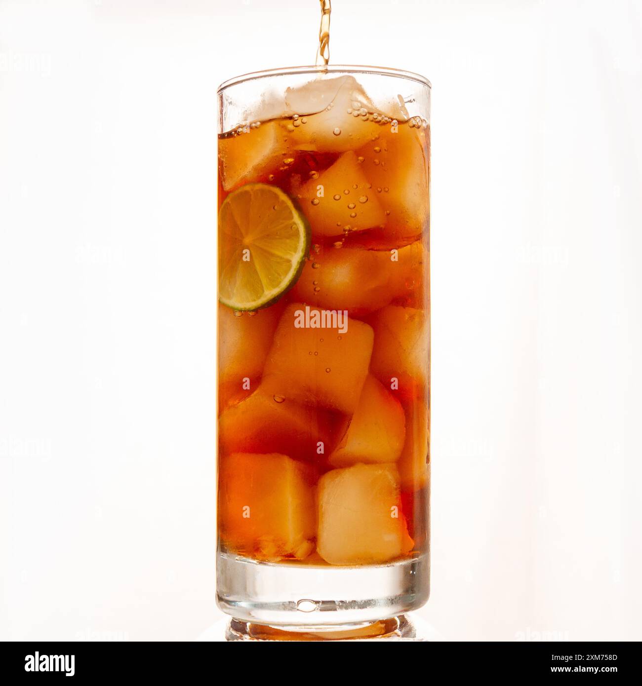 topping off cola over ice in tall glass with lime slice Stock Photo - Alamy