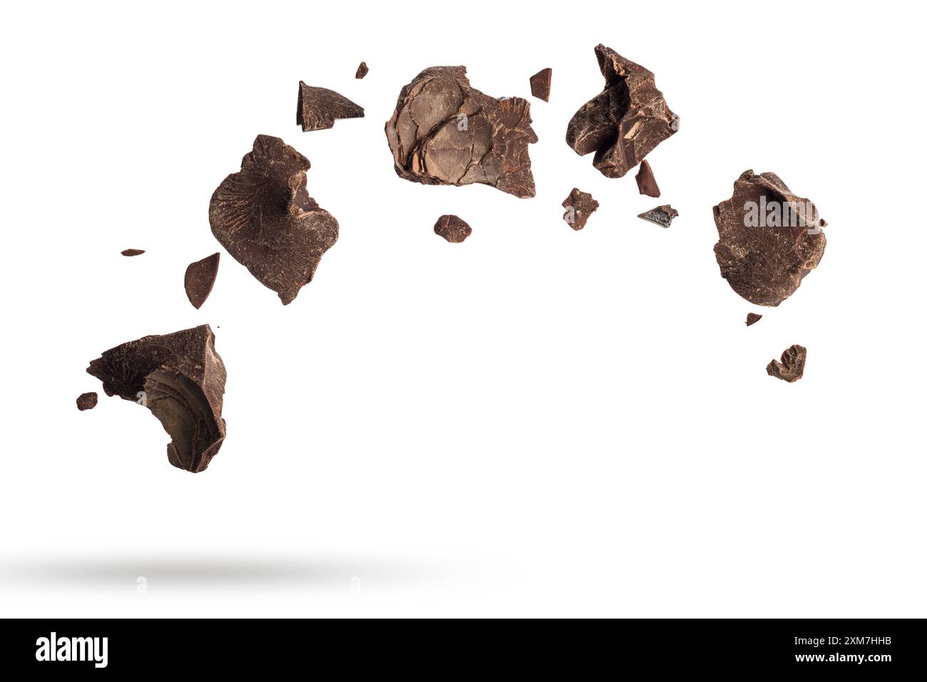 Dark chocolate flakes falling, isolated on white background. Stock Photo