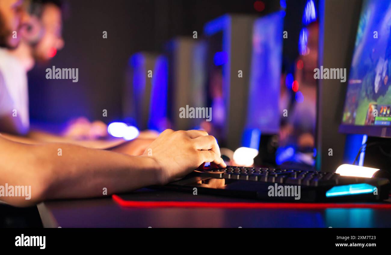 Gamers play video game on PC at computer club, professional cyber sport tournament, gaming mouse RGB lighting keyboard on mat close up. E-sport champi Stock Photo