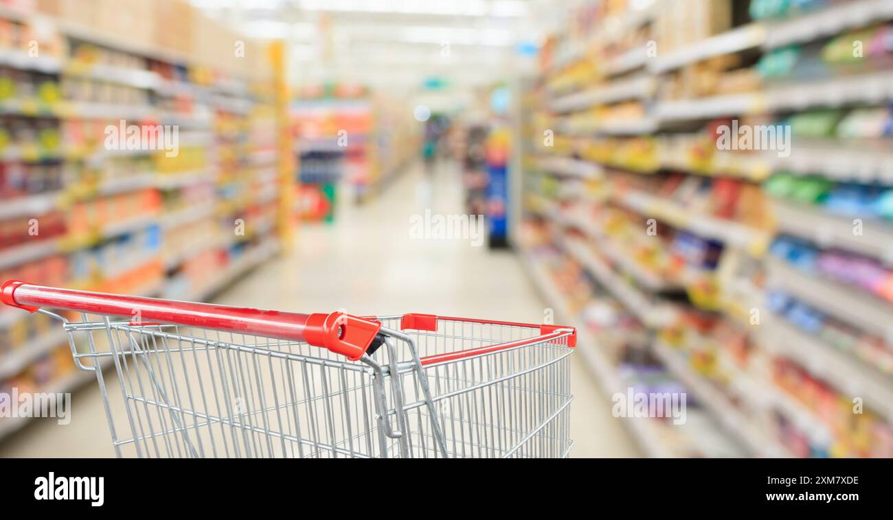 Supermarket aisle blurred background with empty red shopping cart Stock ...