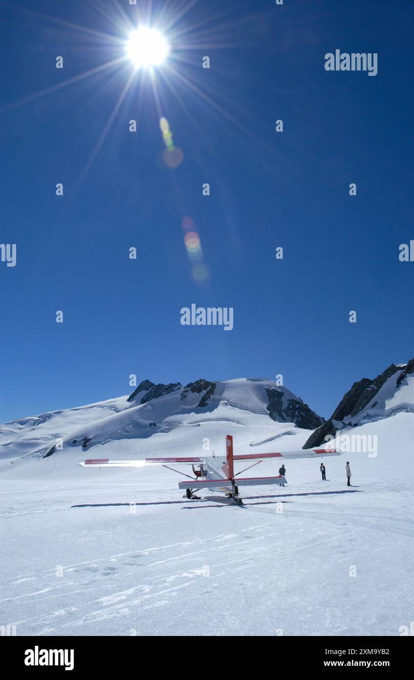 Tourists with aircraft on snowy Mount Cook in New Zealand. With an elevation of 3,724 meters, Mount Cook is the highest mountain in New Zealand, making it a popular climbing destination for mountaineers. Stock Photo