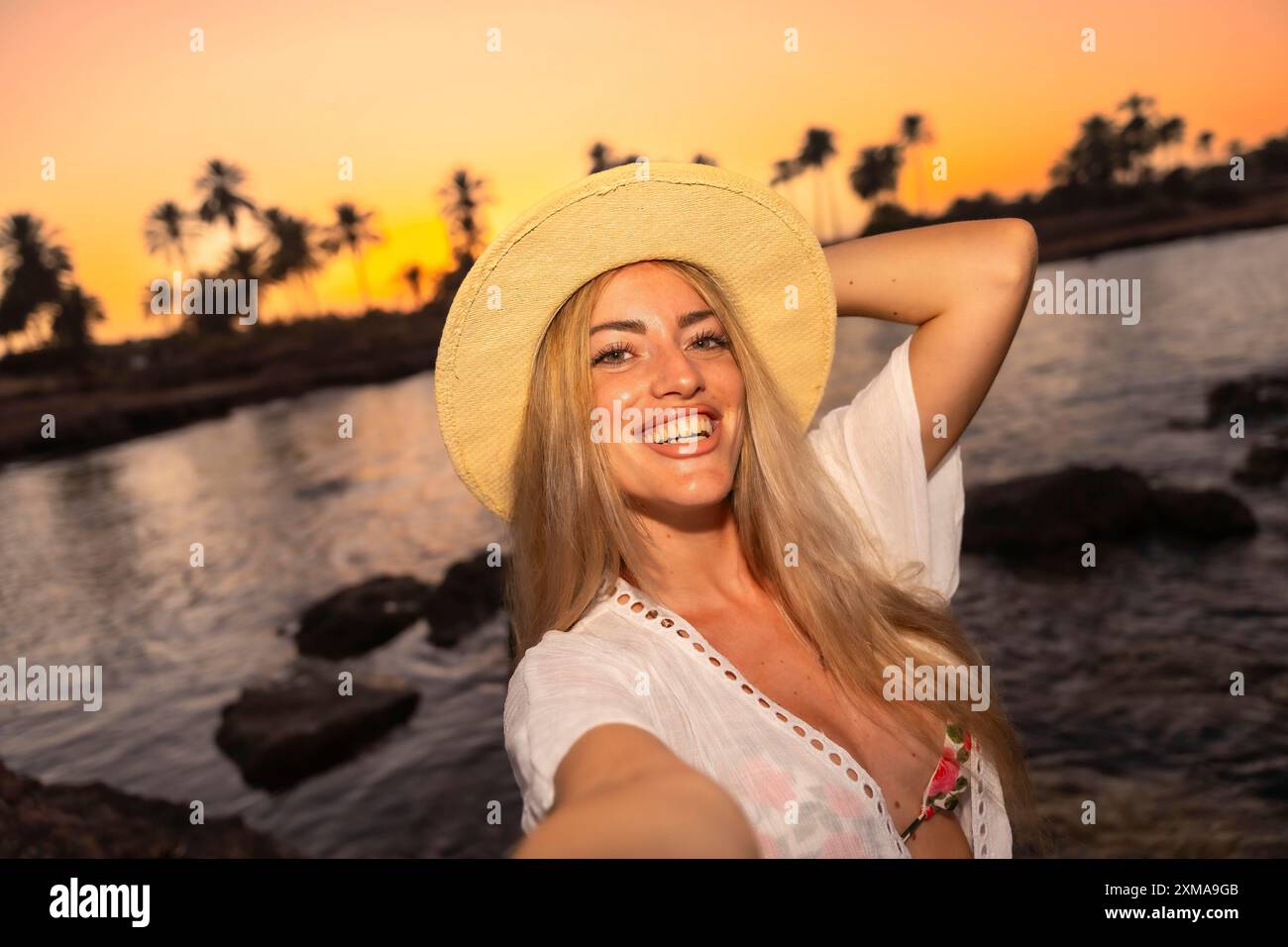 Personal point of view of a a happy woman taking selfie during sunset while enjoying beach day Stock Photo