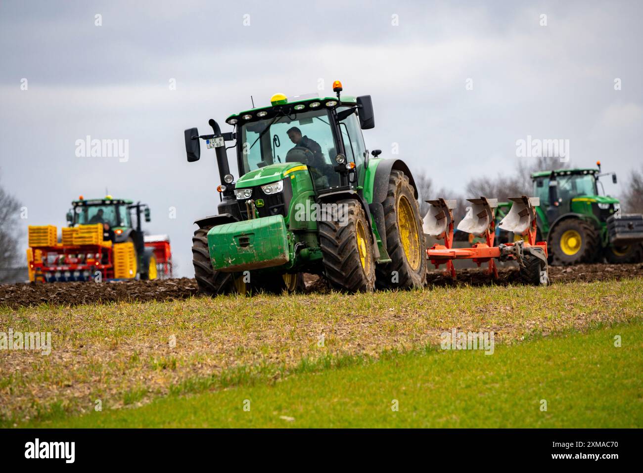 Tractor with a plough preparing the soil of a field for planting ...