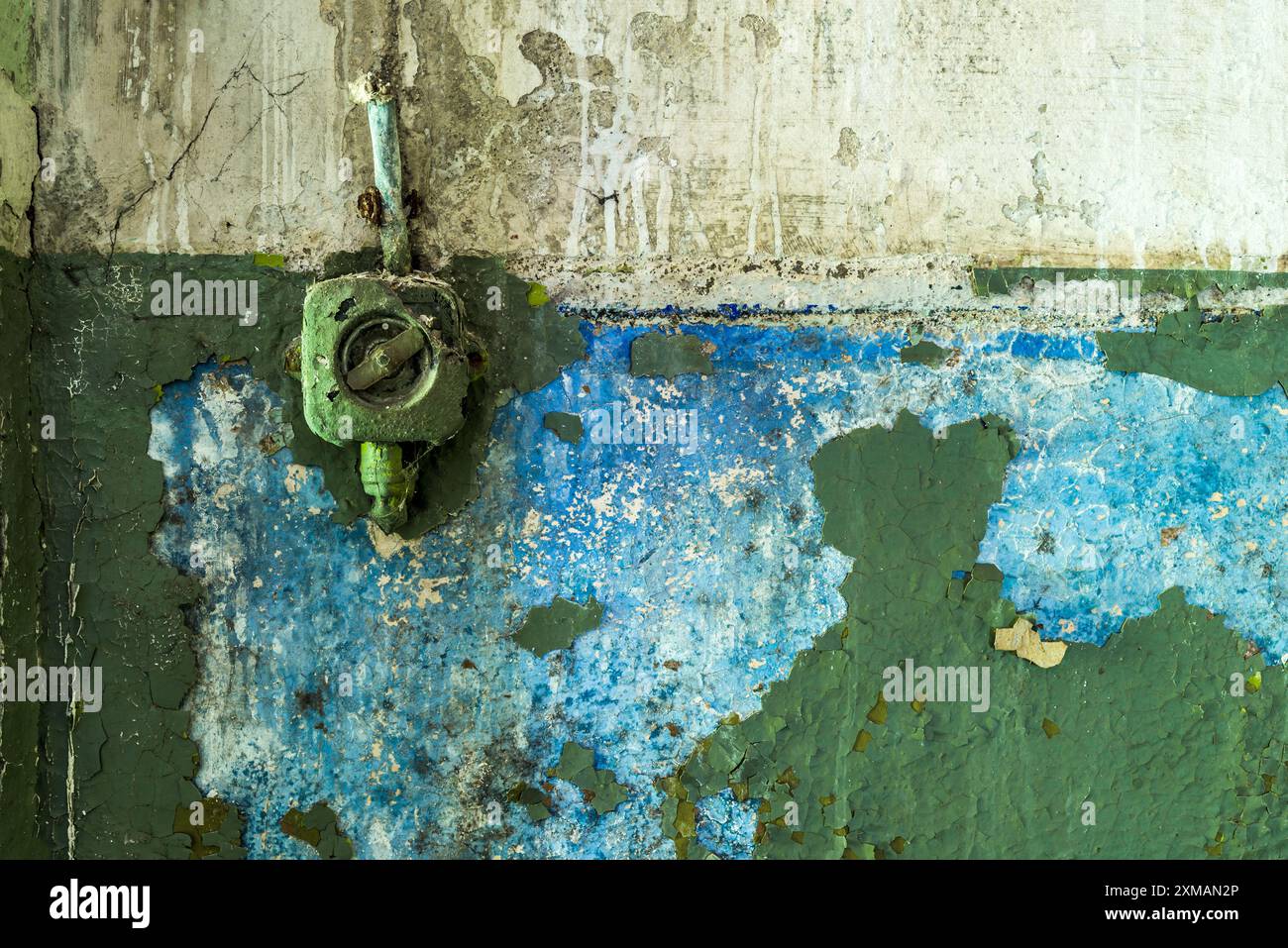 Old painted plastic rotary light switch on a grunge green peeling concrete wall background Stock Photo