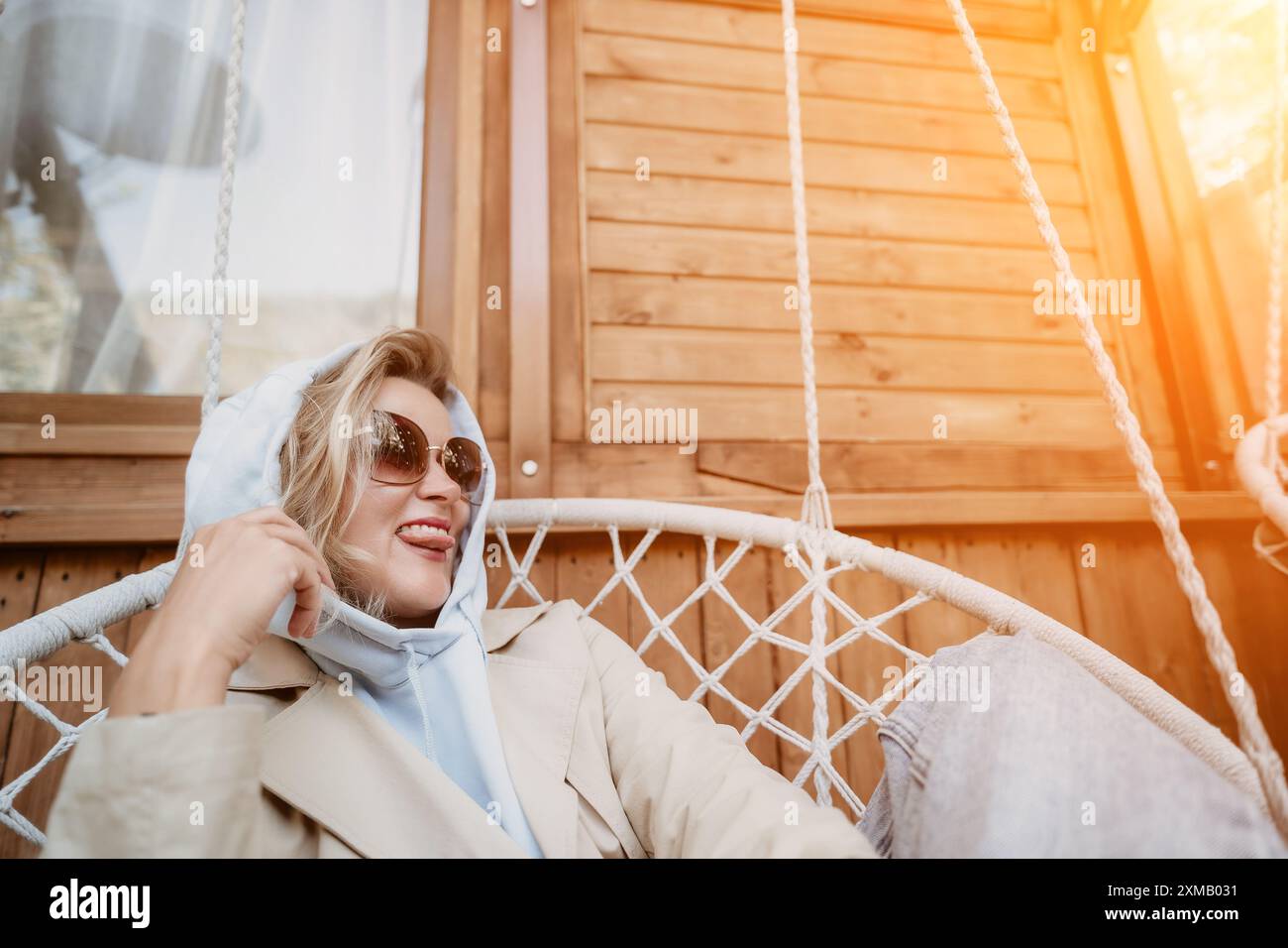 Woman Relaxing in a Hanging Chair on a Patio Stock Photo - Alamy