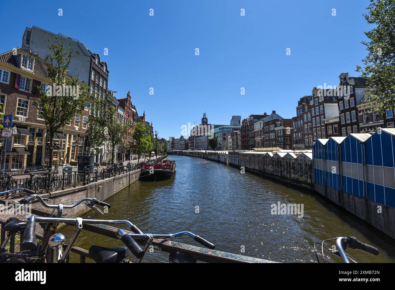 The Floating Flower Market (Bloemenmarkt) and Traditional Dutch Buildings along a Charming Canal on a Sunny Day - Amsterdam, Netherlands Stock Photo