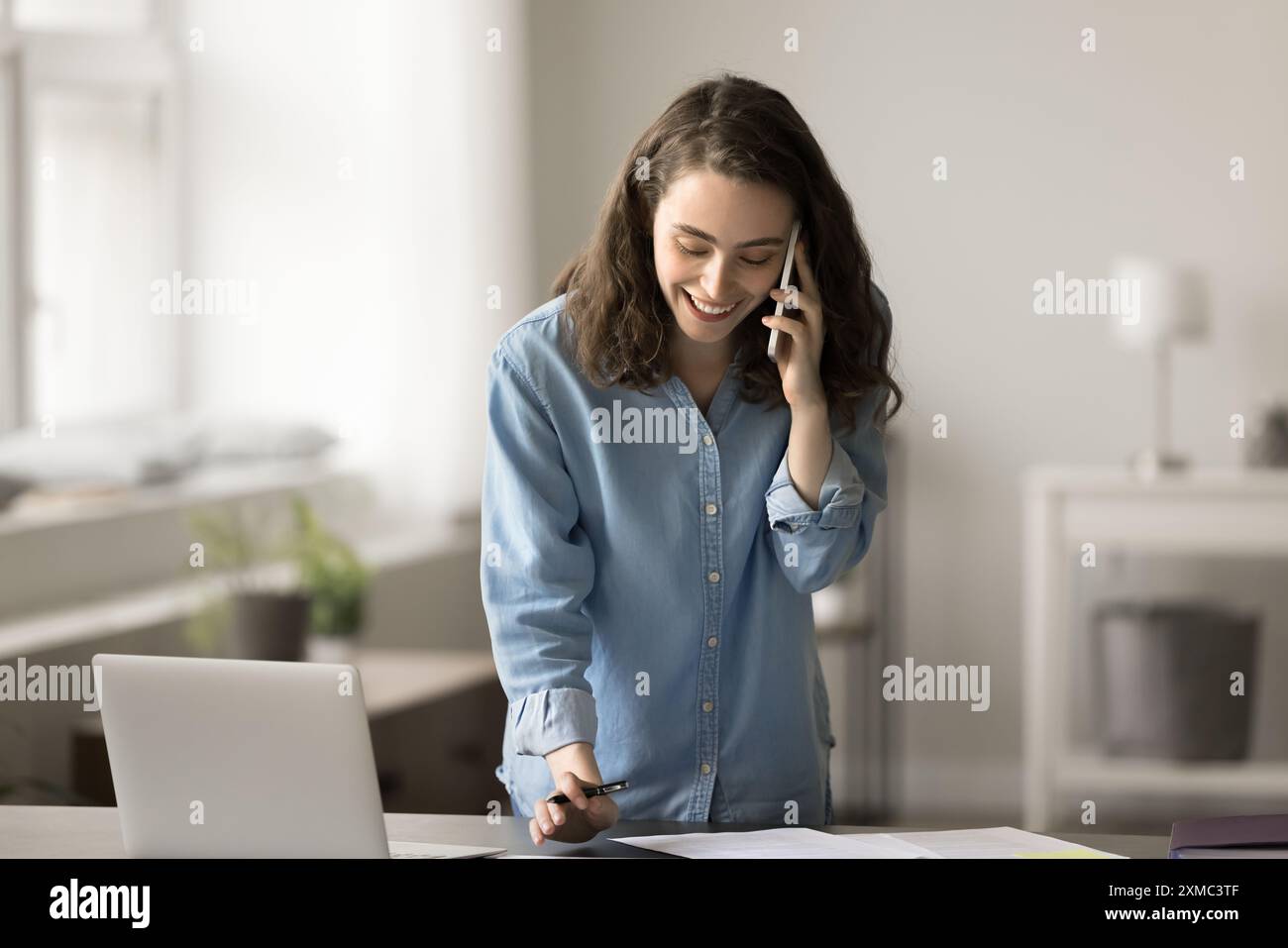 Woman talking to client, making notes, working remotely Stock Photo