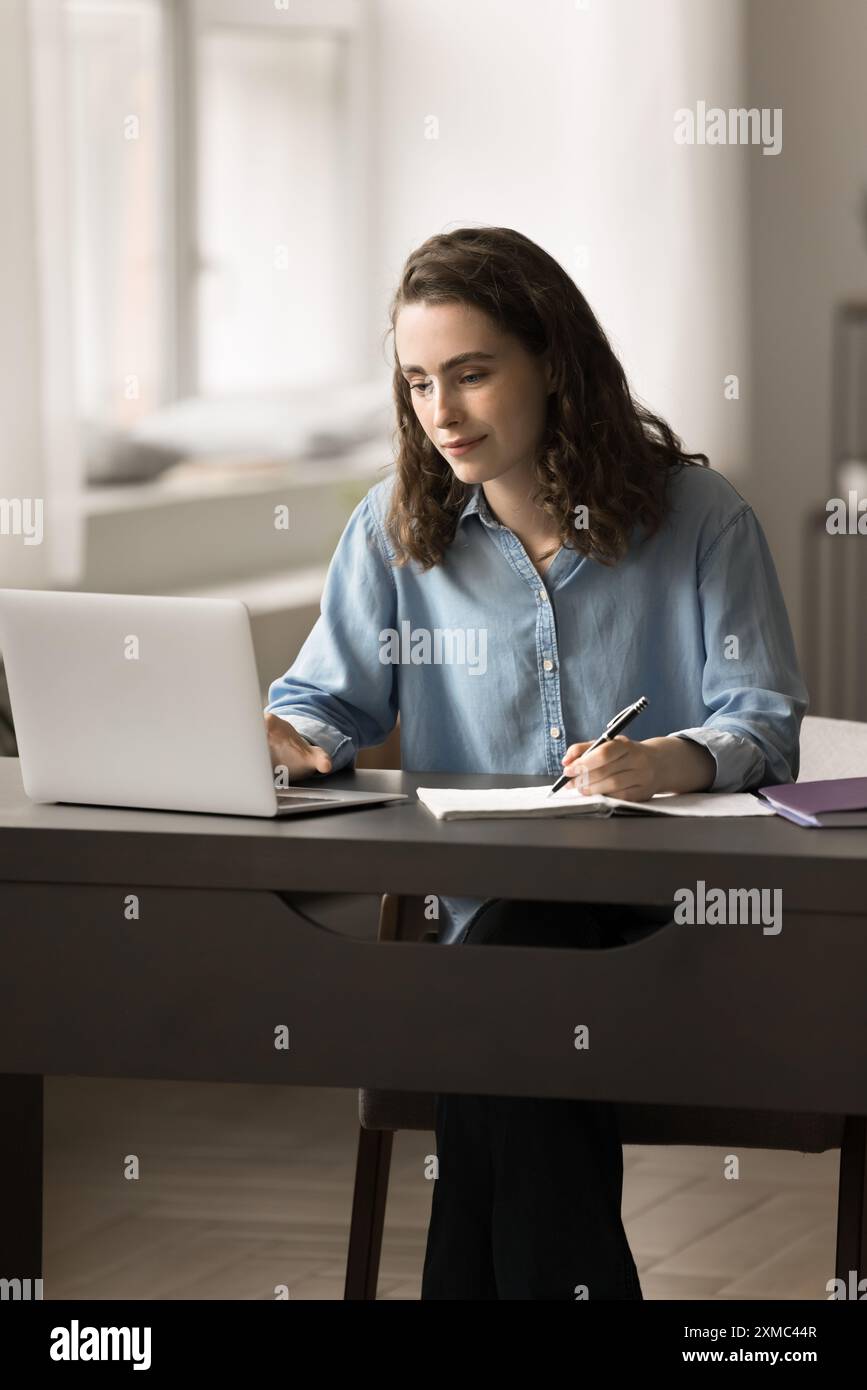 Focused school girl sits at table studying with laptop Stock Photo - Alamy